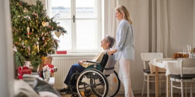 Woman standing by elderly woman in wheelchair