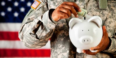 Man in military uniform holding piggy bank