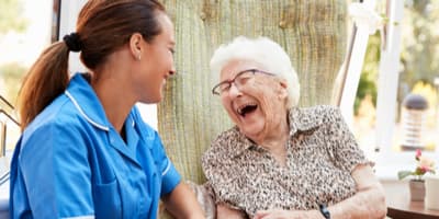 Nurse and elderly woman laughing