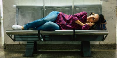 young adult sleeping on subway bench